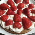 Gâteau aux fraises sans gluten avec crème chantilly, présenté sur une assiette blanche.
