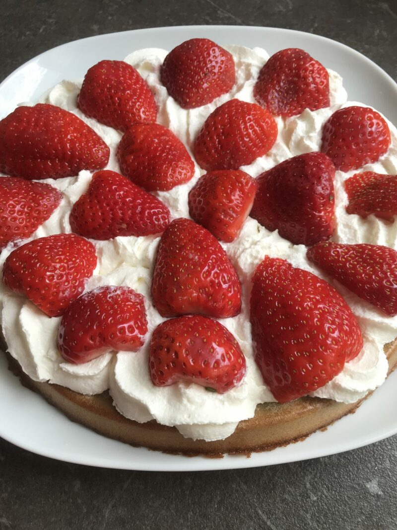 Gâteau aux fraises sans gluten avec crème chantilly, présenté sur une assiette blanche.