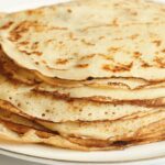 Pile de crêpes dorées sans gluten sur une assiette blanche