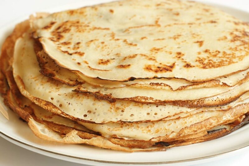 Pile de crêpes dorées sans gluten sur une assiette blanche