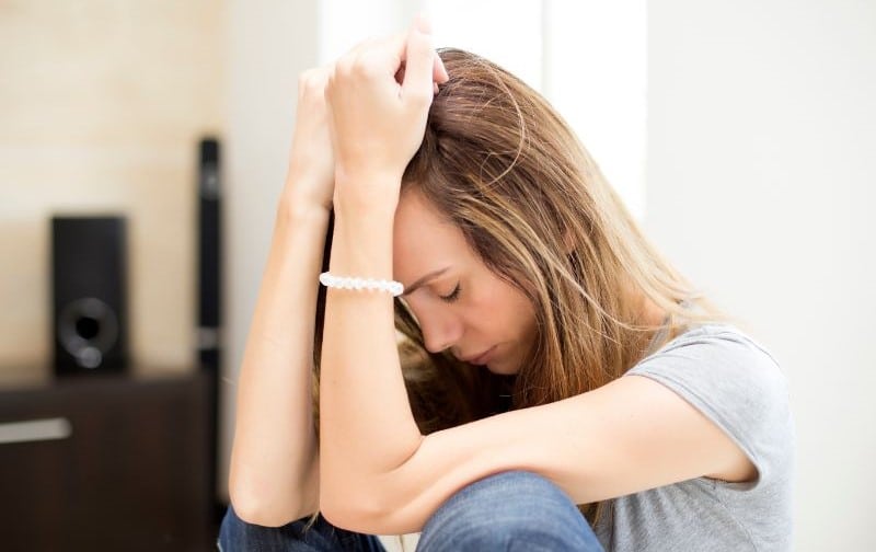 Femme en détresse tenant sa tête avec les mains, symbolisant la découverte de son intolérance au gluten.
