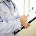 Médecin tenant un clipboard avec un stéthoscope autour du cou.