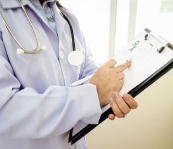 Médecin tenant un clipboard avec un stéthoscope autour du cou.